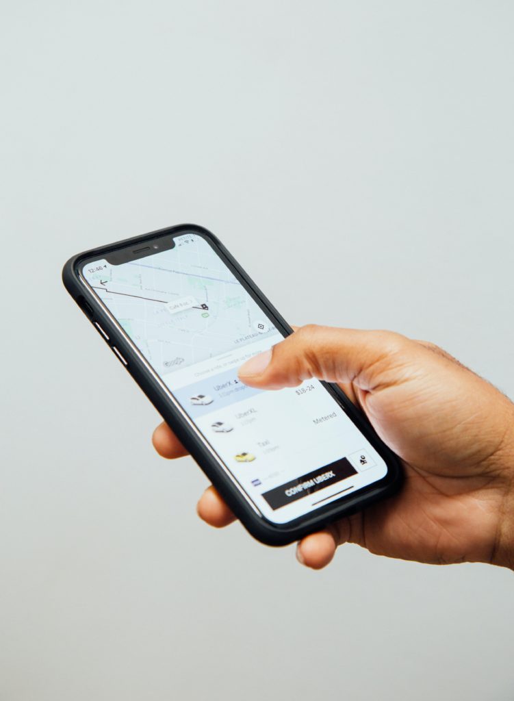 Man's hand holding a phone that is using the Uber app.